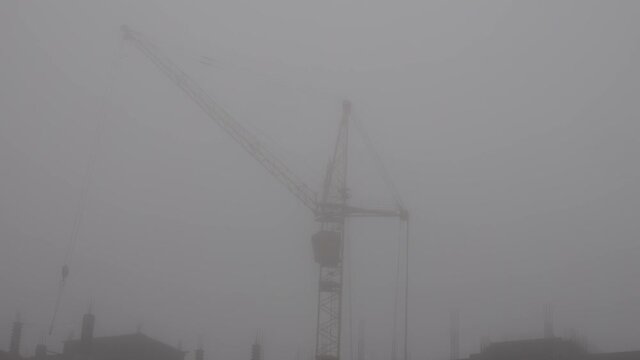 construction site a crane in fog is building residential building
