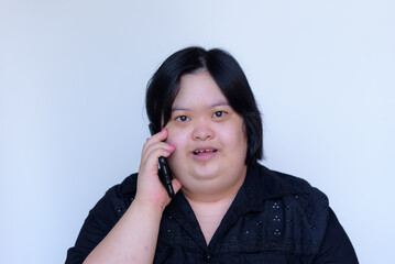 Close-up of an Asian girl with a disability. Down syndrome children. Talking on the phone and smiling happy on a white background Concept: Down Syndrome