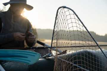 Net for pulling fish out of the water in an inflatable boat, against a blurred background, a fisherman prepares for fishing, at dawn.