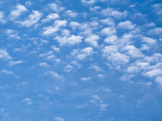 Many small white clouds run across the crystal blue sky. Beautiful natural, heavenly background.