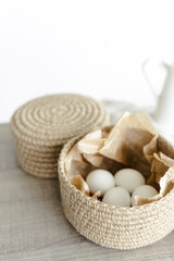 Handmade home decor made from organic jute fiber. Two wicker jute baskets are placed on a wooden table. White chicken eggs in a basket. The concept of Easter decor.