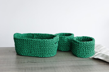 rectangular basket with green handles woven from knitwear on the table. white background
