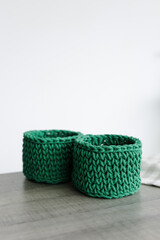 round baskets of green color on the table woven from knitwear on a white background