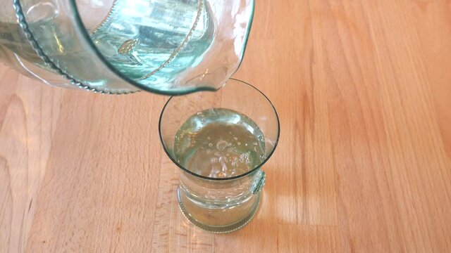 Pouring water and preparing fizz drink from water and effervescent tablet. Wooden table in the kitchen.