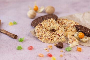 Cookies, candied fruits, nuts and a stick of cinnamon on a pink background. Close-up. Space for text