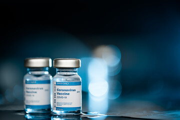 Two Covid-19 vaccine vials on blue background to inject people at risk.