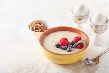 Healthy breakfast - oatmeal with berries and nuts in a bowl on the table.