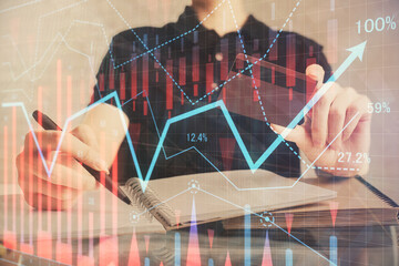 Double exposure of man hands holding a credit card and Forex graph drawing. Stock trading and digital fintech in Internet E-commerce concept.