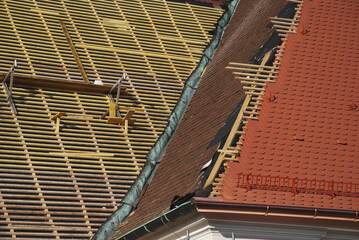 Ein Steildach wird mit Biberschwanz Ziegeln gedeckt. Zu sehen sind der Unterbau des Daches mit den...