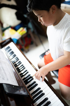 A boy is studying piano online with tablet.