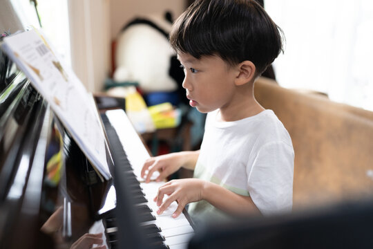A boy is studying piano online with tablet.