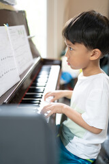 A boy is studying piano online with tablet.