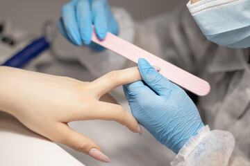 process of filing nails manicure in the salon, removing gel polish or acrylic from long nails