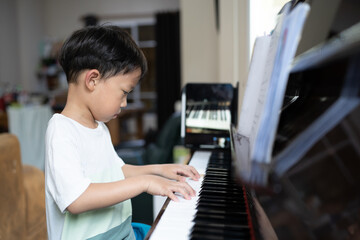 A boy is studying piano online with tablet.