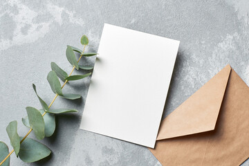 Greeting card mockup with envelope and eucalyptus twigs on grey concrete background
