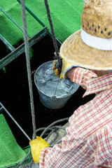 Obraz premium Farmer with straw hat drawing fresh water from a well in the contryside.