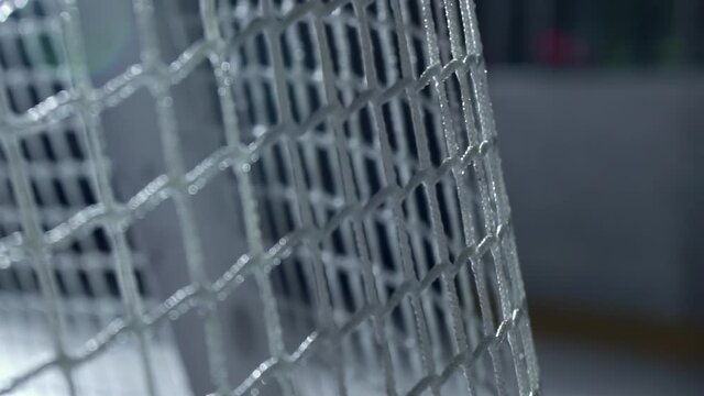 Hockey puck flies into goal net in slow motion close-up