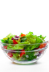 various fresh mix salad leaves with tomato in glass bowl isolated on white background