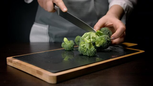 Female hands cut broccoli in pieces. Slicing florets from broccoli stem