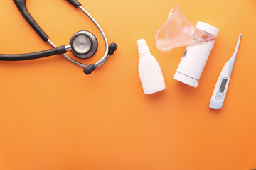 nebulizer , thermometer and stethoscope on orange background 