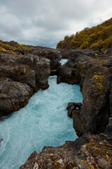 Fototapeta na wymiar Unusual blue waterfall in Iceland Hraunfossar