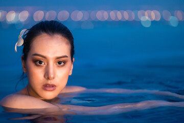 Asian young woman relax in swimming pool at luxury hotel spa enjoying beautiful .Close up Female Enjoying Summer Travel in City Hotel. vacation woman in bikini .