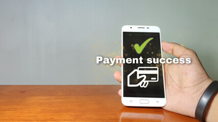 Online shopping concept, young man hands holding mobile phone showing payment success information on screen on table while relax at home.