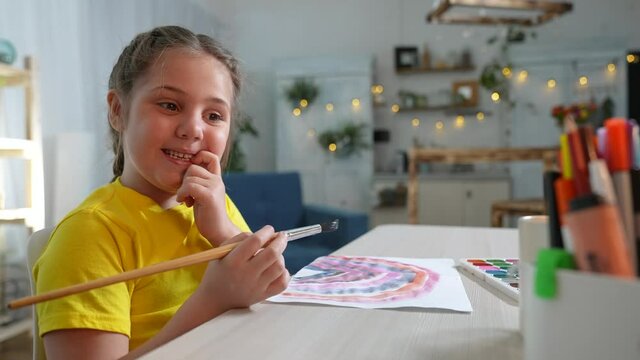 Child girl drawing a rainbow. child artist draws at the table in kindergarten. coronavirus stay home pandemic concept. kid draws indoor a rainbow. school kindergarten drawing lesson