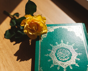 Close up Quran (holy book in islam) and rose (islamic symbol) on the table in the sunlight