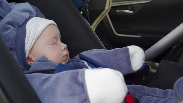 Cute baby boy sleeping in infant car seat while having a ride in backseat. High quality 4k footage