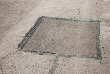 Cracked asphalt road surface and repair patch closeup
