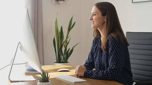 Confident business woman takes a part in video meeting on the PC computer, female employee wearing smart casual shirt greeting participants of online discussion,video call and video conference concept