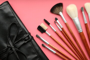 Top view of case and makeup brushes set on pink background 
