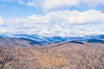 Panorama of spring hills turning into snow-capped mountains