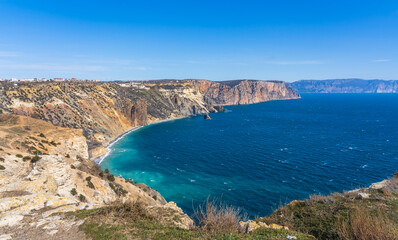 View of the Black Sea from Cape Fiolent in sunny weather. Blue sea water, blue sky contrasts with yellow coastal rocks