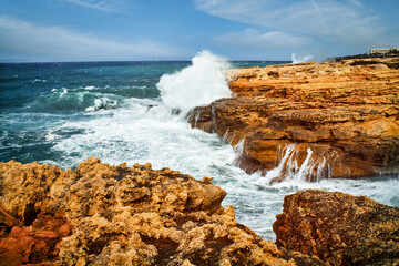 Splashing waves crashing against the rocks on the shore.