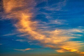 Fototapeta na wymiar Сolorful cirrus clouds in warm colors from the setting sun against a blue sky.