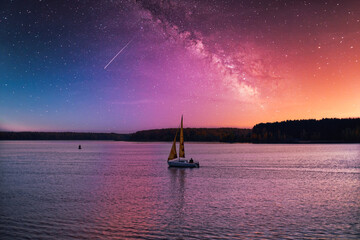 A small sailboat floats on the lake against the backdrop of a picturesque evening sky.