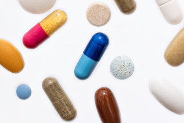 Close-up colorful powder soft capsules pill vitamin blue pink yellow brown supplements on white background