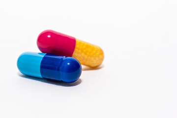 Close-up colorful powder soft capsules pill isolated on white. blue pink yellow medicine supplement vitamin