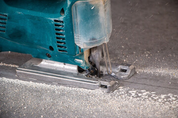 male hands of construction worker sawing and cutting parts with an electric hand jigsaw from  panel. the process of cutting building board for interior decoration with an electric jigsaw
