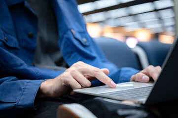 business man sitting and using laptop computer to work at the airport, young person go to travel journey and having internet communication technology for work when waiting indoor at airport departure