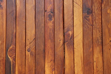 The texture of pine wood planks painted in brown and coated with wood oil. 