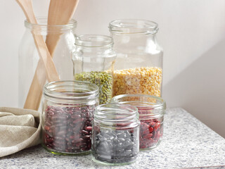 Variety of dry legumes: kidney bean, peas, green gram in glass jars uncooked on white kitchen background, zero waste, eco friendly, balanced diet food, healthy clean eating, vegan protein concept