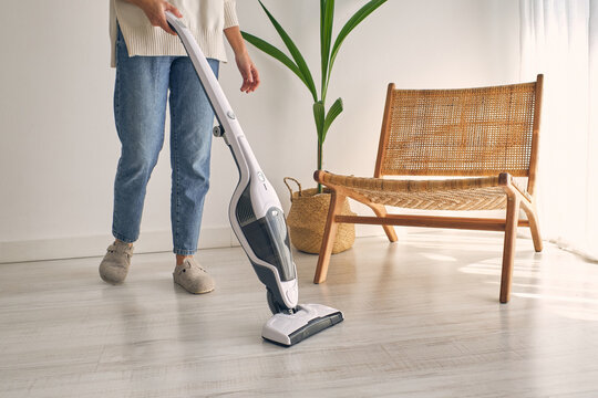 Anonymous Woman Vacuuming Floor In Modern Minimalist Apartment