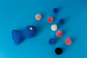 fun knitting project of blue fish with yarn pompoms 