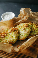 Vegetable zucchini pancakes with sour cream sauce on a wooden board