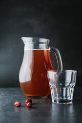 Delicious healthy rosehip drink in a glass decanter on a dark background. Brown apricot juice or cocktail