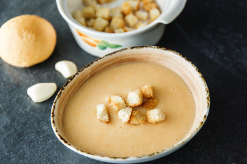 Cream soup of broccoli, potatoes, carrots with croutons on a dark background