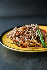 Asian style buckwheat noodles with soy sauce, vegetables, sesame seeds and herbs